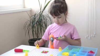 Kız bir tornavida, bir tornavida ve çok renkli geometrik şekilli shurukalar ile Çocuk Eğitimi İnşaatçısı yapbozu oynuyor. yaratıcı anaokulu geliştirme kavramı