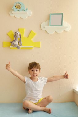 Şık ve modern iç tasarım. Çocuk odası için geldim. Çocuk yenilenmiş odada seviniyor. Sade bej bir duvarda beyaz bulutlar şeklinde çocuk rafları ve fotoğraf çerçevesi..