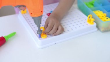 Tornavida, tornavida ve çoklu renkli geometrik incirli shurukalar ile Çocuk Eğitimi İnşaatçısı yapbozu oynayan bir çocuğun yakın çekimi. yaratıcı anaokulu geliştirme kavramı