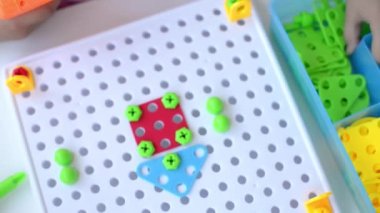 Tornavida, tornavida ve çoklu renkli geometrik incirli shurukalar ile Çocuk Eğitimi İnşaatçısı yapbozu oynayan bir çocuğun yakın çekimi. yaratıcı anaokulu geliştirme kavramı.