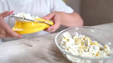 Anaokulu öğrencisi kız çocuk mutfakta yemek pişiriyor. Hurda malzemelerle günlük hayatta iyi motor becerilerin geliştirilmesi. Çocuk yumurtaları sarı bir yumurta kesiciyle kesiyor..