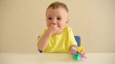 Küçük çocuk beyaz bir masada otururken inşaatçıyı oynuyor. Eğitici oyun Montessori güzel motor becerileri. Erken gelişim konsepti. Tehlikeli oyuncakları ağzına alır..