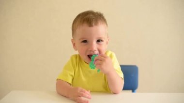 Küçük çocuk beyaz bir masada oturan kırmızı bir kalemle bir kağıt parçasına resim çizer. Eğitici oyun Montessori güzel motor becerileri. Erken gelişim kavramı