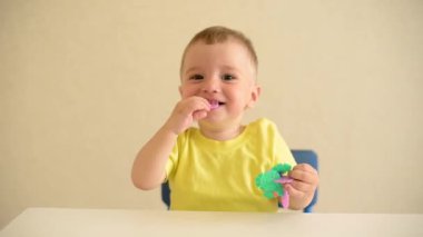 Küçük çocuk beyaz bir masada otururken inşaatçıyı oynuyor. Eğitici oyun Montessori güzel motor becerileri. Erken gelişim konsepti. Tehlikeli oyuncakları ağzına alır..