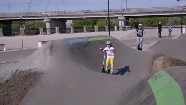 今夏清晨 一位身穿黄色短裤和白色T恤的女孩骑着两轮滑板车 坐在公园的滑梯上 儿童发展和暑假的概念 — 图库视频影像
