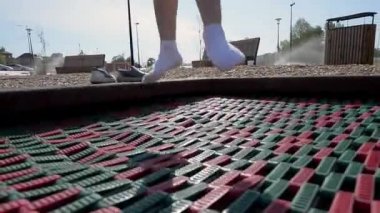 Sarı şertas ve beyaz tişörtlü bir kız yaz sabahı bir çocuk parkında trambolinde zıplıyor. çocuklar dinlenme konsepti
