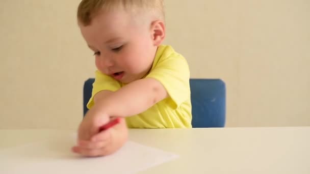 Малыш Играет Ничью Листе Бумаги Красной Ручкой Сидящей Белым Столом — стоковое видео
