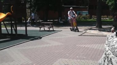 Baba ve kızı parkta tek bir elektrikli scooter kullanıyor. Elektrikli araç kiralama kavramı