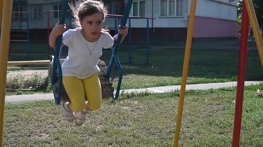 Anaokulu kızı yaz sabahının erken saatlerinde evin yakınındaki parkta salıncakta sallanıyor. Çocuk eğlencesi ve eğlencesi konsepti