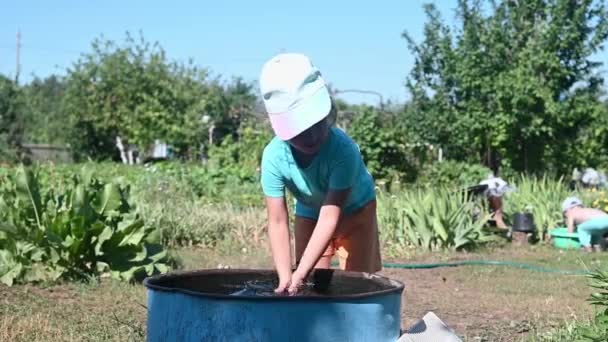 未就学児は庭のダチャの暖かい水で樽に手を洗う 子供を硬化させる 水の樽の中でただ単に — ストック動画