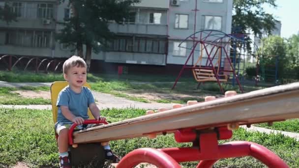 Menino Joga Nos Passeios Playground Balanço Balança Balanceador — Vídeo de Stock