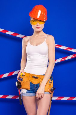 Koruyucu bir kask içinde bir profesyonel yapı aracı ile mavi bir arka plan Oluşturucu kız