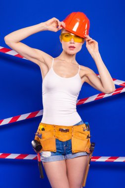 Koruyucu bir kask içinde bir profesyonel yapı aracı ile mavi bir arka plan Oluşturucu kız