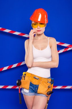 Koruyucu bir kask içinde bir profesyonel yapı aracı ile mavi bir arka plan Oluşturucu kız