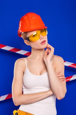 Koruyucu bir kask içinde bir profesyonel yapı aracı ile mavi bir arka plan Oluşturucu kız
