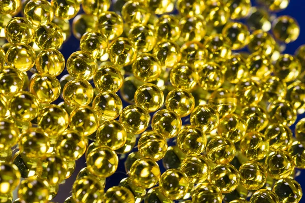 Cápsulas médicas amarillas en una superficie de espejo — Foto de Stock