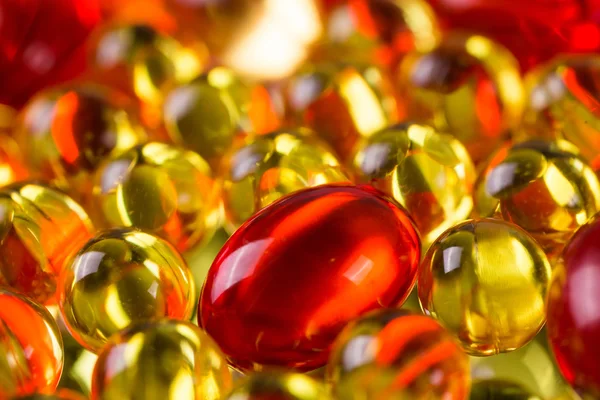 Yellow and red medical capsules on a mirror surface — Stock Photo, Image