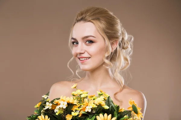 Blondin med blommor i händerna — Stockfoto