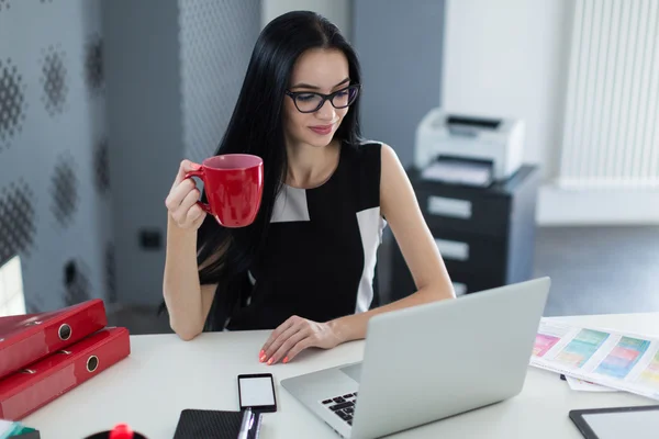 Деловая женщина в очках с чашкой кофе в офисе — стоковое фото