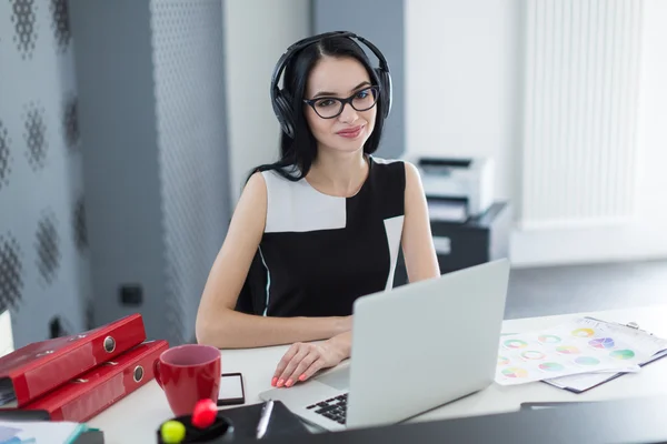 Bilgisayarbaşında çalışan kulaklıkile ofiste iş kadını — Stok fotoğraf