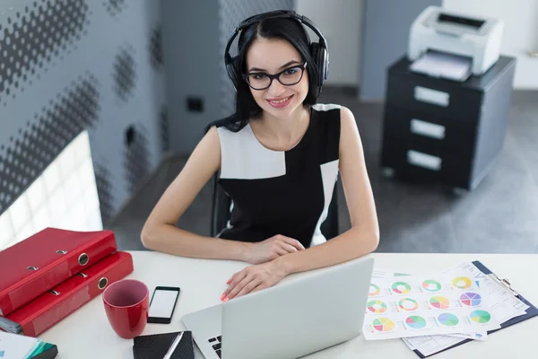 Деловая женщина в офисе с наушниками, работающими за компьютером — стоковое фото