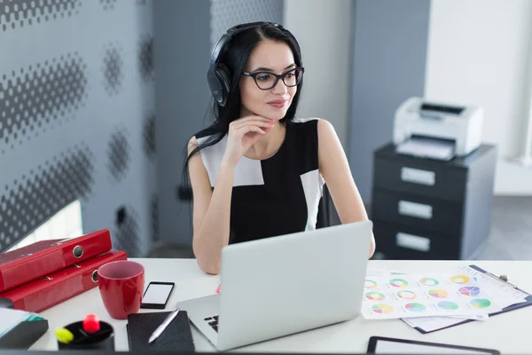 Femme d'affaires dans le bureau avec écouteurs travaillant à l'ordinateur — Photo