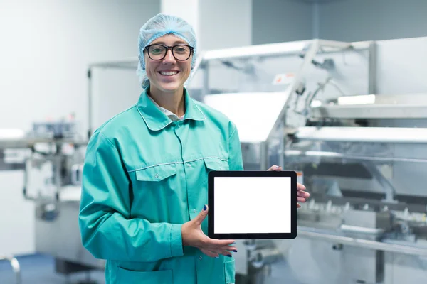 Trabajador de la fábrica farmacéutica con una tableta en sus manos muestra Equipo — Foto de Stock