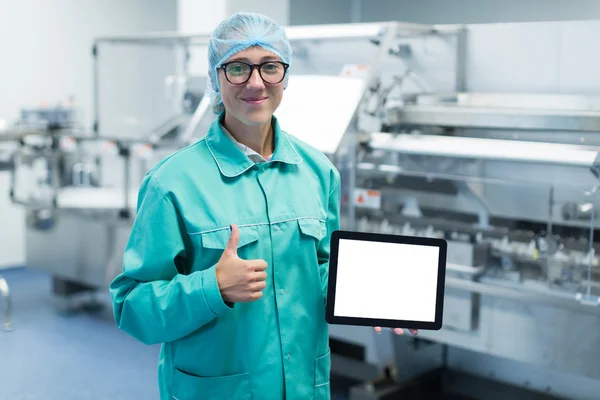 Trabajador de la fábrica farmacéutica con una tableta en sus manos muestra Equipo — Foto de Stock