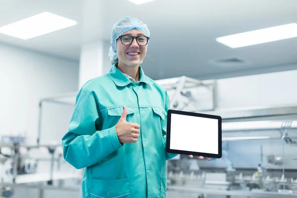 Trabajador de la fábrica farmacéutica con una tableta en sus manos muestra Equipo —  Fotos de Stock