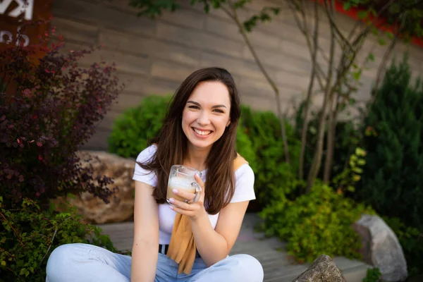 Щаслива молода жінка сидить у прекрасному парку і п'є гострий латекс — стокове фото