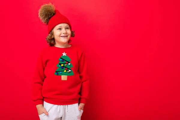 Känslomässigt porträtt av en tonåring på en röd bakgrund i en nyårsdräkt — Stockfoto