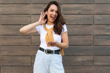 Kahverengi arka planda yalnız poz veren genç kadın, stüdyo portresi. İnsanların yaşam tarzı konsepti. Kopyalama alanı oluşturun. Cep telefonu kullanmak, SMS iletisi yazmak