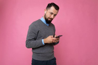 Pembe arka planda yakışıklı bir adam cep telefonuyla mesaj gönderiyor.