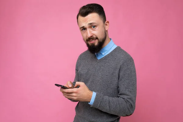 분홍색 배경을 다루는 잘생긴 남자가 핸드폰으로 메시지를 보내는 모습 — 스톡 사진