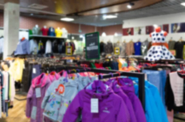 Market with hanging clothes on hangers, Blurred photo — Foto Stock