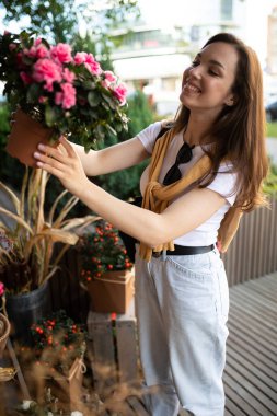 Bahçedeki yazlık dükkandan çiçek alan çekici genç bir kadın.