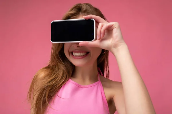 Close-up Foto de bela sorridente jovem boa aparência vestindo casual roupa elegante de pé isolado no fundo com espaço de cópia segurando smartphone mostrando telefone na mão com tela vazia — Fotografia de Stock