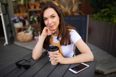 Dışarıda öğle arasında kahve içen çekici genç bir kadın.