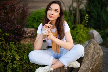Kahve molası veren çekici genç iş kadını kafe terasında oturuyor.