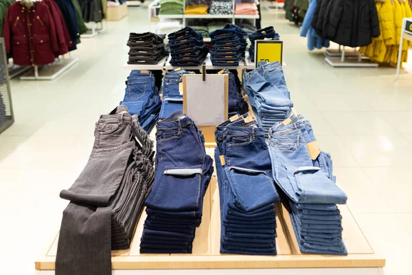 Obchod s oblečením s velkým sortimentem kalhot a džín zavěšených na ramínku — Stock fotografie