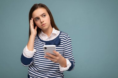Arkaplanda izole edilmiş, el ele tutuşmuş ve cep telefonu mesajları kullanan sıradan şık kıyafetler giyen çekici ve hoş görünümlü genç bir bayanın fotoğrafı.