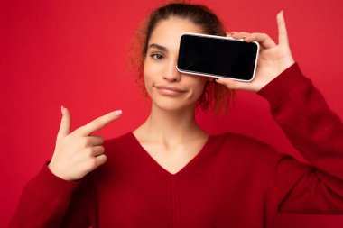 Güzel, gülümseyen genç bir kadının resmi. Günlük kıyafetlerini giymiş. Arka planda izole bir şekilde duruyor.