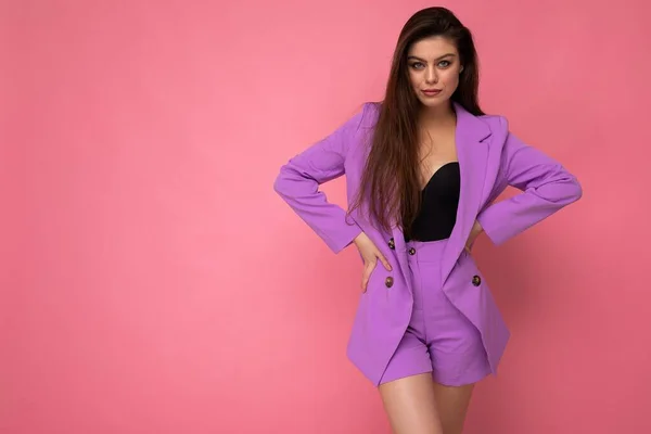 Portret van zelfbewuste serieuze mooie modieuze brunette vrouw in casual stijlvolle violet pak geïsoleerd over roze achtergrond met kopieerruimte. Bedrijfsconcept — Stockfoto