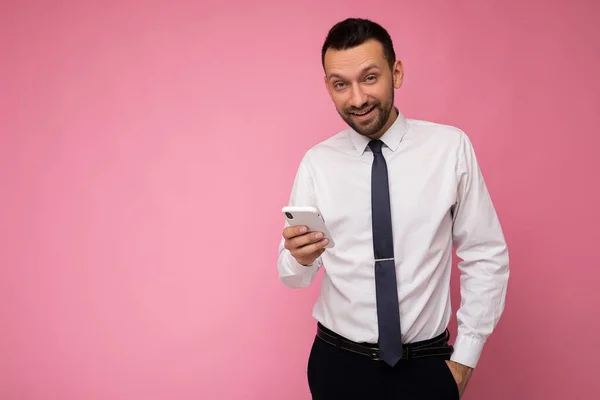 Foto tiro de bonito positivo bom olhar adulto empresário vestindo roupa elegante casual poising isolado no fundo com espaço vazio segurando na mão e usando sms de mensagens de telefone móvel — Fotografia de Stock