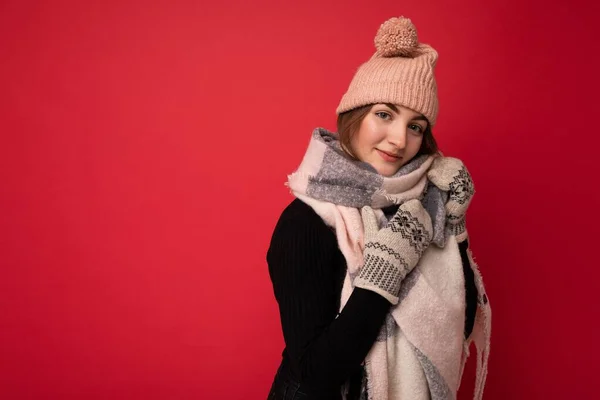 Foto der schönen glücklichen netten jungen brünetten Frau isoliert über rotem Hintergrund Wand trägt Winter Schal Fäustlinge und warmen Hut Blick in die Kamera und träumen — Stockfoto