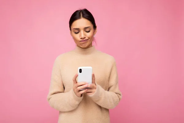 Gyönyörű fiatal nő visel alkalmi ruhát áll elszigetelt háttér szörfözés az interneten keresztül telefonon nézi a mobil képernyőn — Stock Fotó