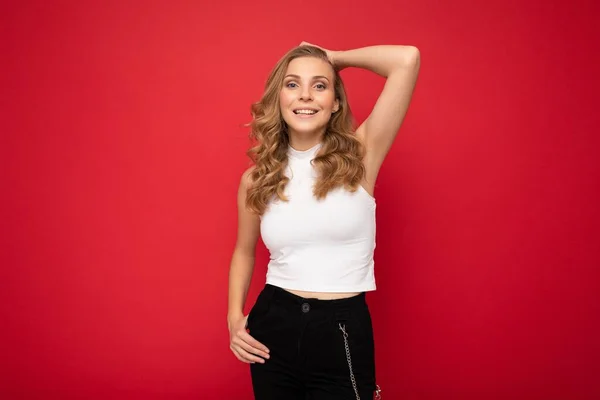 Photo of young charming fascinating sexy attractive happy smiling delightful blonde woman with sincere emotions wearing stylish clothes posing isolated over red background with copy space — 스톡 사진
