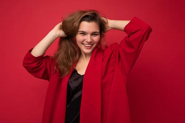 Junge schöne europäische stilvolle brünette Frau trägt schwarze Bluse Top und rote Strickjacke isoliert über rotem Hintergrund mit positiven aufrichtigen Emotionen. Einfacher und natürlicher Blick auf die Kamera. Frei — Stockfoto