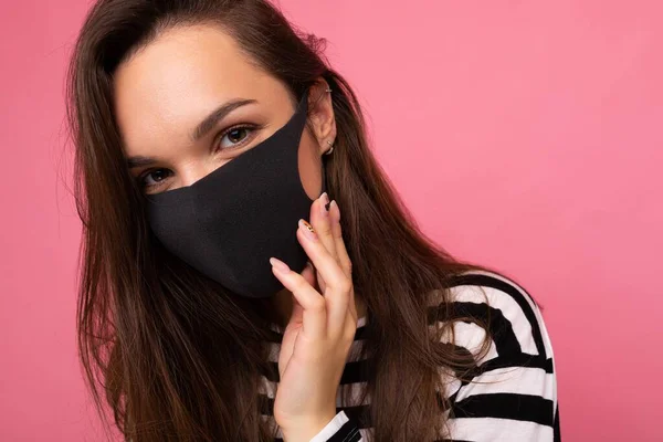 Aufnahme einer jungen attraktiven Frau mit medialer Gesichtsmaske, isoliert über einer rosafarbenen Hintergrundwand. Schutz gegen COVID-19 — Stockfoto