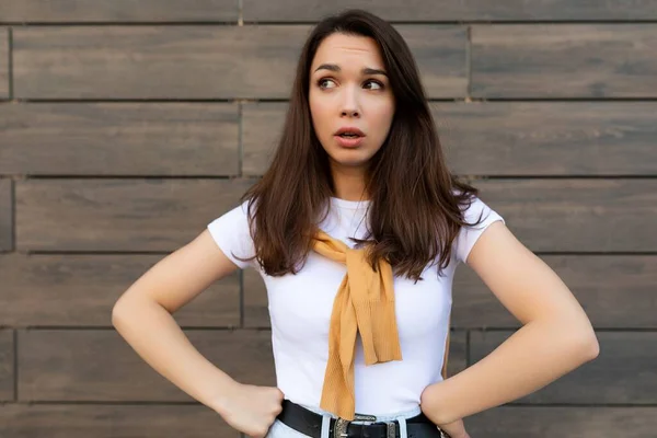 Photo of thoughtful thinking pretty young brunette woman in trendy outfit. Beautiful attractive female person standing outside in the street and having doubts — Stock Photo, Image